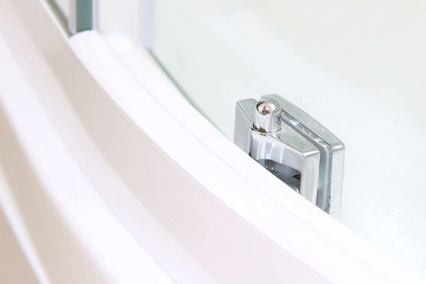 Polished chrome pivot hinge connecting a glass shower door to a white curved frame with a dark rubber seal