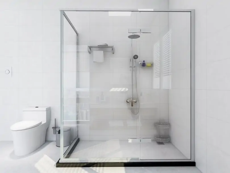 Frameless sliding glass shower enclosure with chrome rain showerhead in a white tiled bathroom next to a toilet