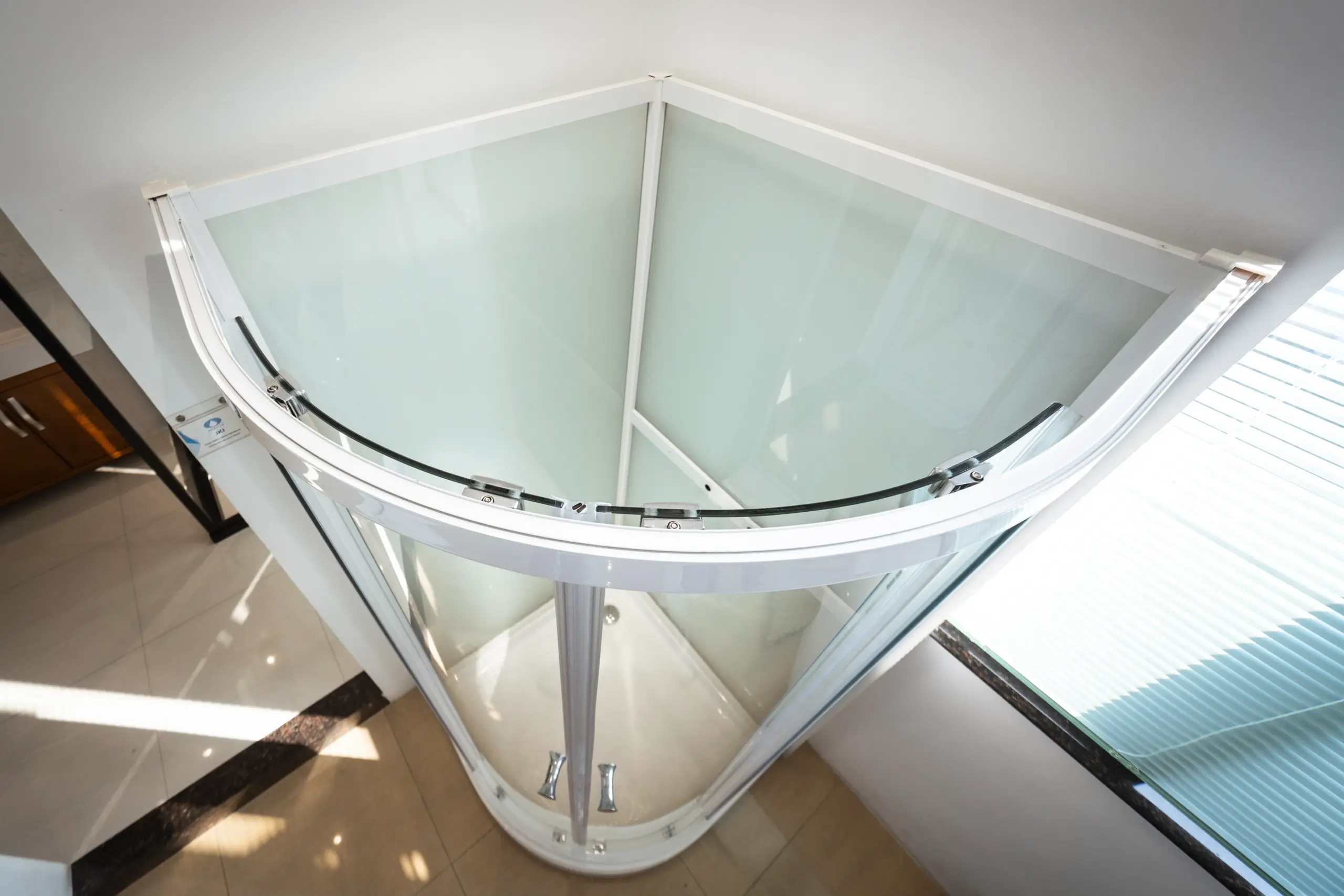 Corner Glass Residential Elevator Modern corner glass elevator with curved design installed in a bright room