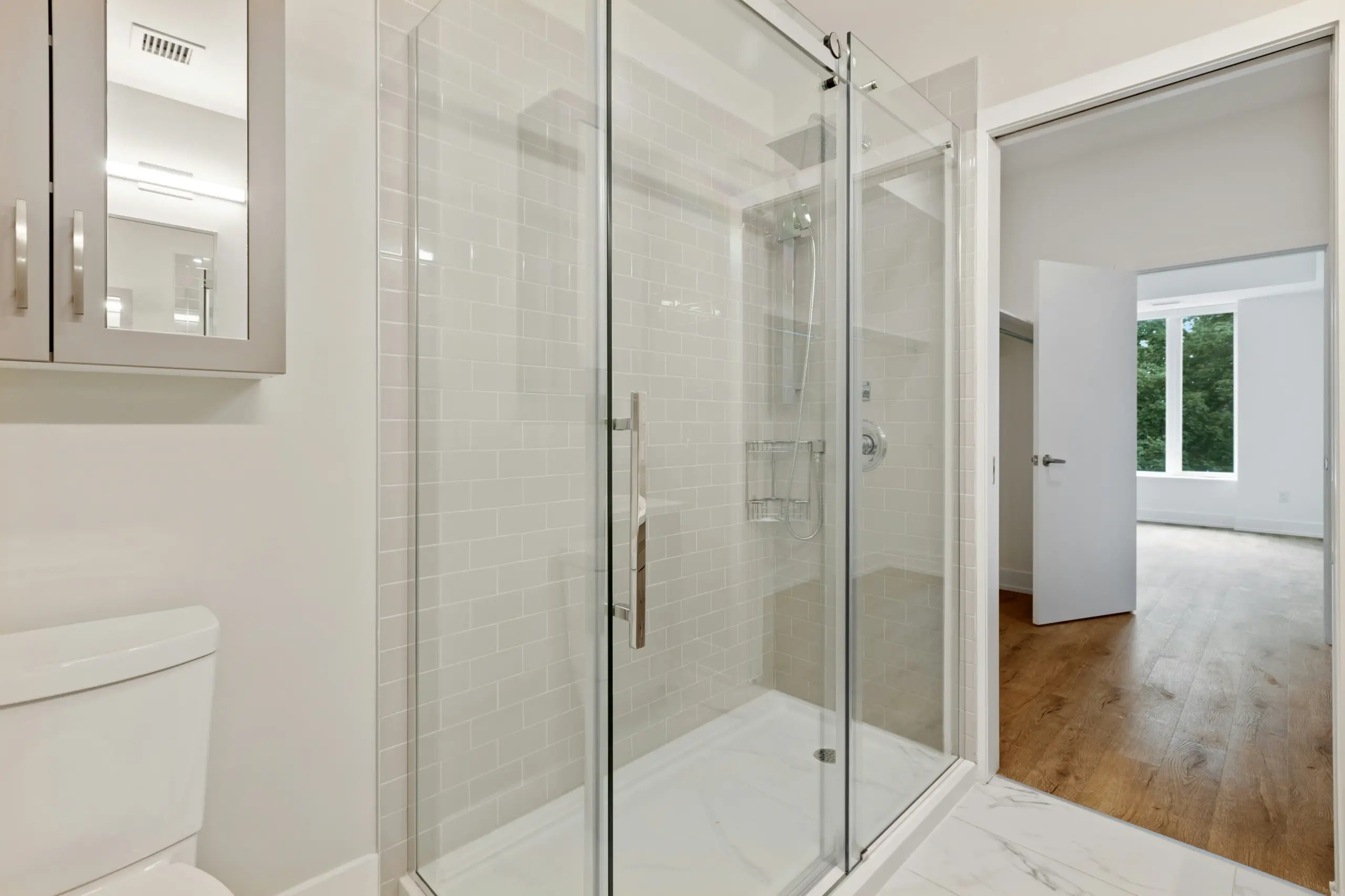 Modern Bathroom with Walk In Shower Bright modern bathroom with glass shower, white subway tile, and view into bedroom