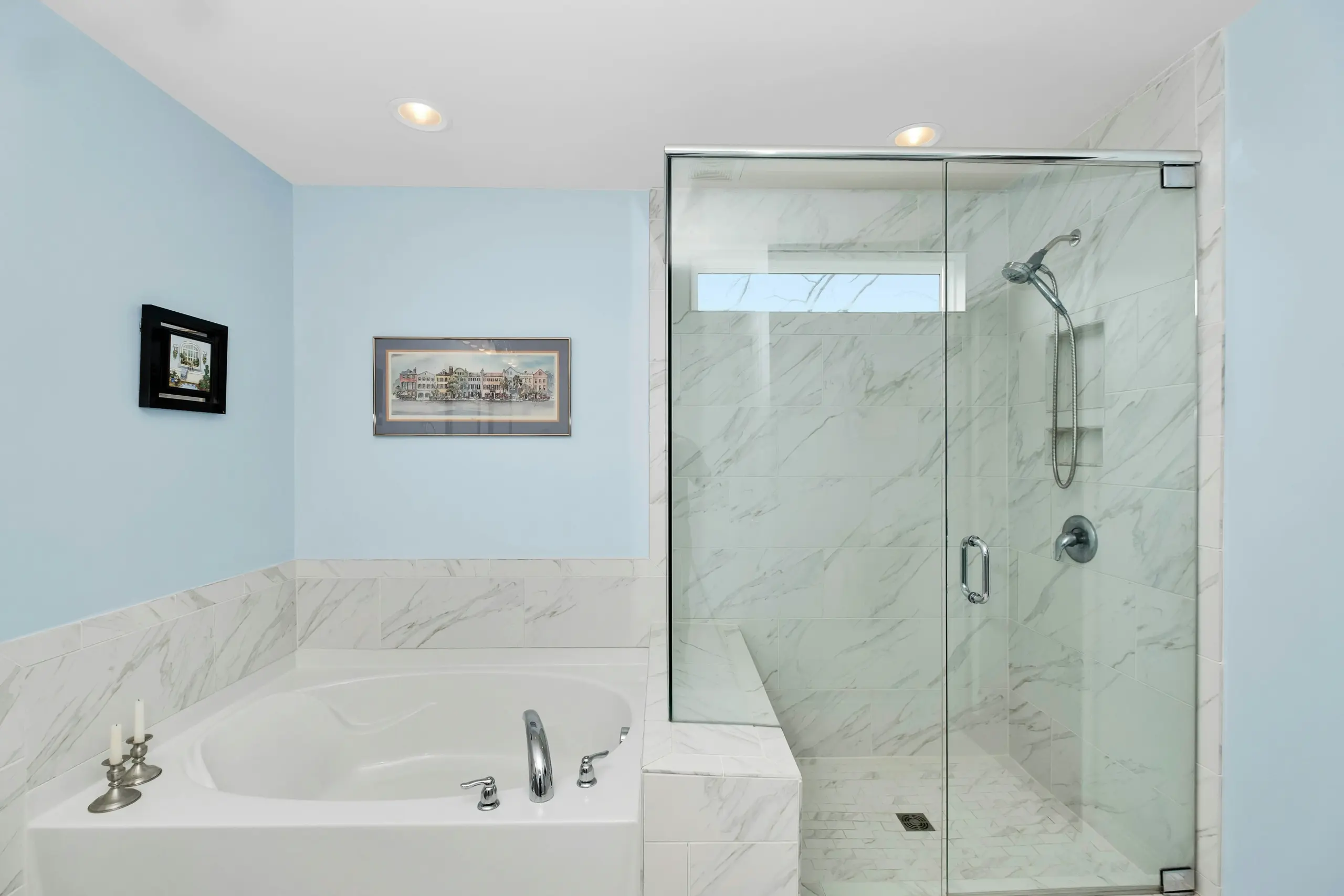 Modern Blue Bathroom with Marble Tub and Glass Shower A modern bathroom with light blue walls, a white marble bathtub, and a glass-enclosed walk-in shower.