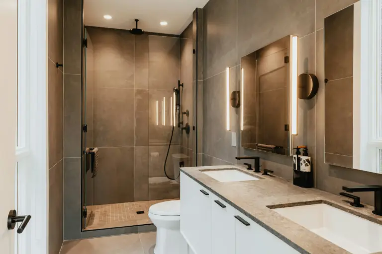Sleek bathroom featuring a walk-in shower, double sink vanity with white cabinets, and vertical LED lighting.