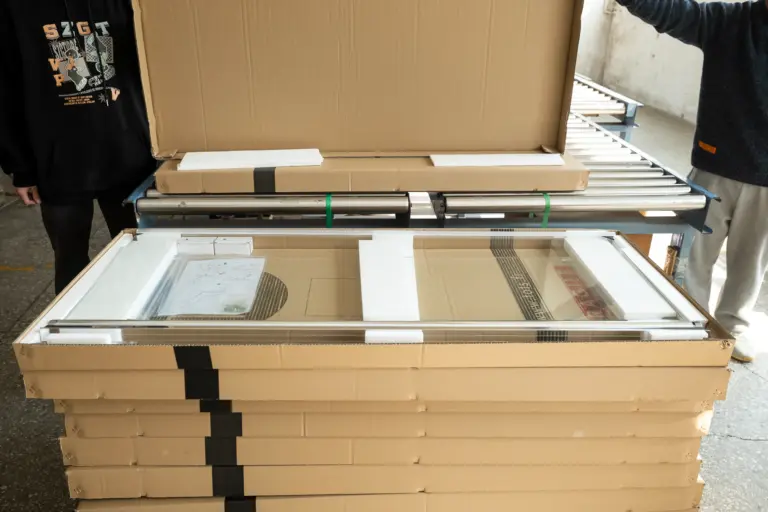 Stacks of packaged glass panels on a roller conveyor system in a warehouse